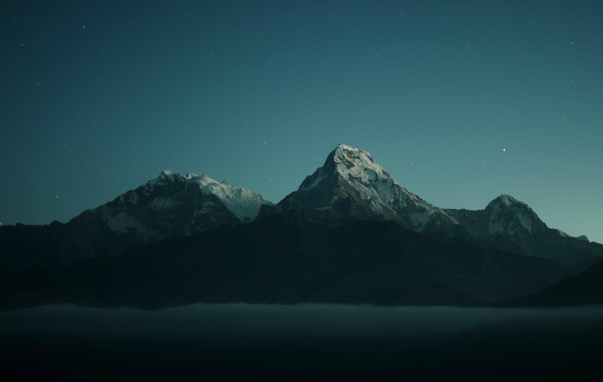 Snowy mountains under a blue and starry night sky